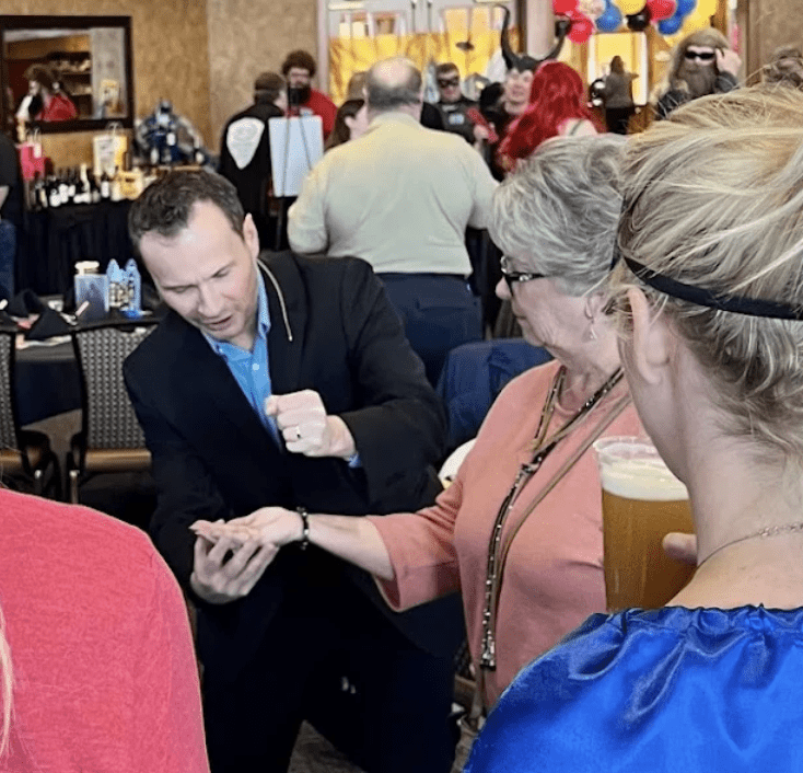 David Farr performing a card trick for guests at a party