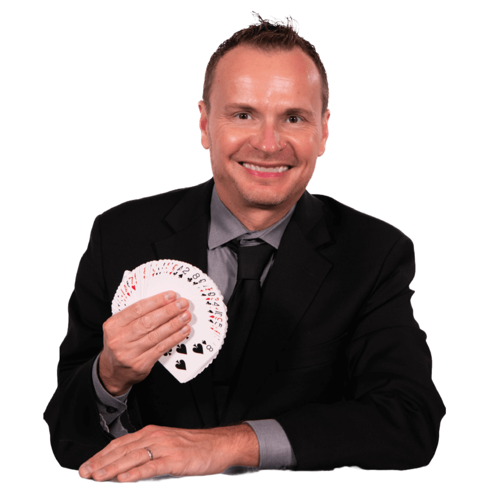 David Farr, magician David Farr in a black suit, smiling and fanning a deck of playing cards