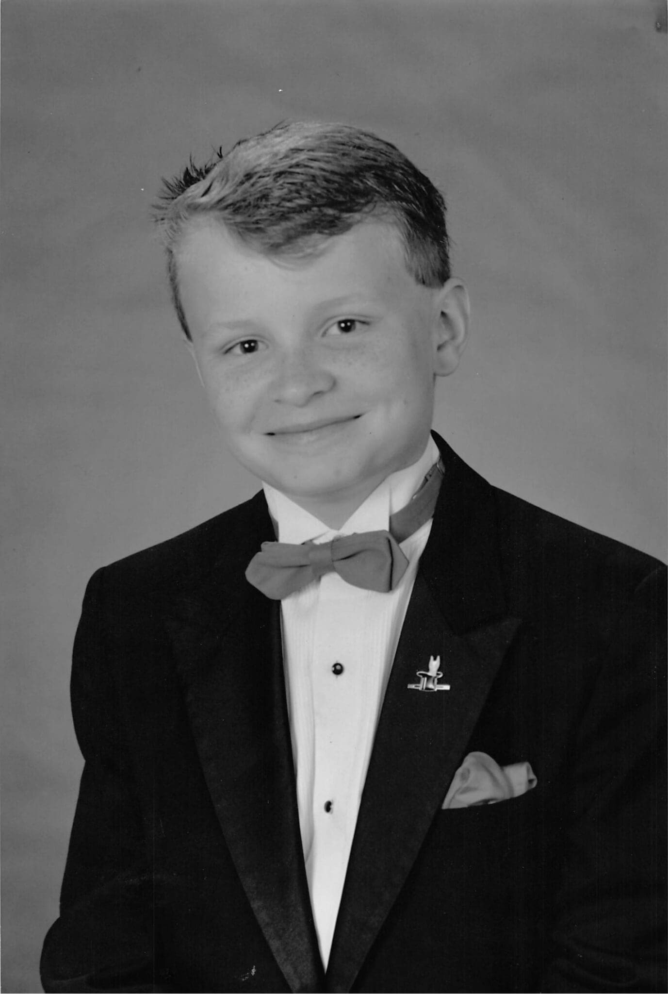 Black and white studio publicity portrait of David Farr at twelve years old, wearing a tuxedo and bow tie