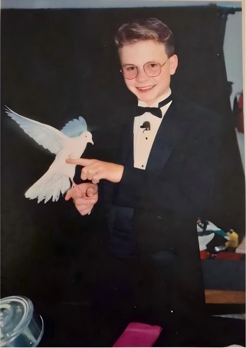 David Farr at fourteen, in a tuxedo on stage, with a white dove landing on his outstretched finger